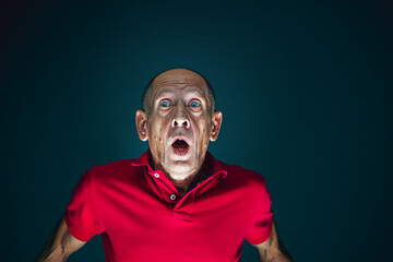 Dumbfounded. Portrait of crazy scared and shocked caucasian man isolated on dark background. Copyspace for ad. Bright facial expression, human emotions concept. Watching horror on TV, cinema.