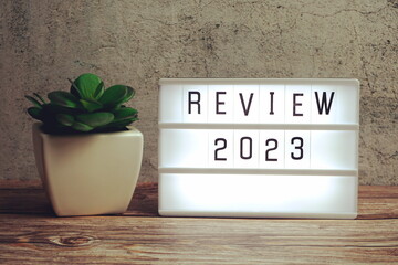 Review 2023 word in light box on wooden background