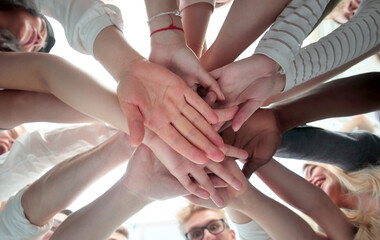 bottom view . group of young people joining their palms together
