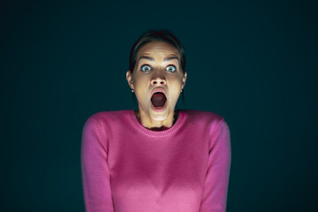 Extreme. Portrait of young crazy scared and shocked caucasian woman isolated on dark background....