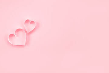 Paper cut hearts on pastel pink background. Composition for Valentine's Day, postcard. Flat lay, top view, copy space.