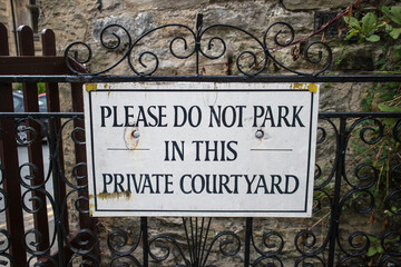 Fototapeta premium Please do not park in this private courtyard information sign on ornate ironwork gate. No parking
