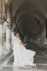 Young woman wearing beautiful white dress in a archway near the Piazza San Marco