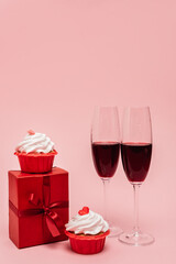 Fototapeta na wymiar red wine near gift and cupcakes isolated on pink