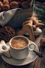Hot flavored nutty cappuccino with caramel and gingerbread Christmas cookies on a rustic table. Vertical shot. Soft focus