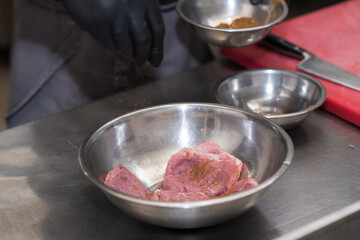 The chef in the restaurant marinates the chicken for the guests
