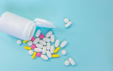 Close-up of a plastic jar with scattered pills on a blue background, the concept of medicine and pharmacy
