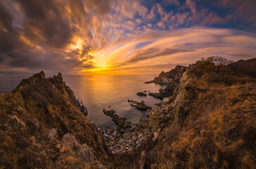 Fototapeta na wymiar Colorful sunset over the cold winter sea and sharp coastal cliffs