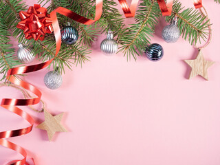 Fir tree branches with christmas decorations on pink 