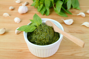 Tasty and Healthy Homemade Fresh Basil Pesto Sauce in White Bowl with a Wooden Spoon