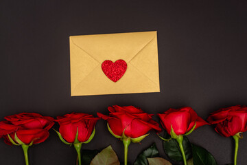 top view of roses and envelope isolated on black
