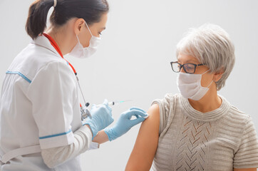 Doctor giving a senior woman a vaccination