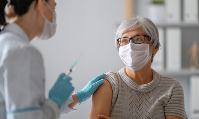 Doctor giving a senior woman a vaccination