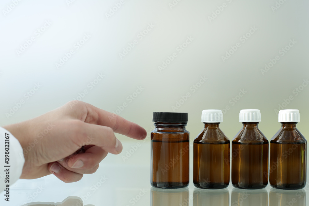 Wall mural The doctor's hand points to one of the four medicine bottles on the glass table.