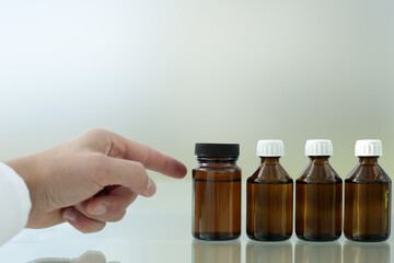 The doctor's hand points to one of the four medicine bottles on the glass table.