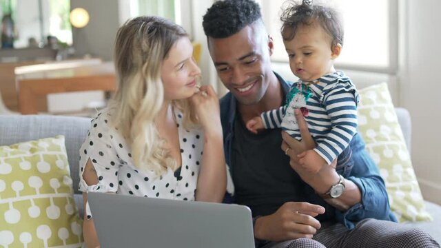 Parents with baby girl using laptop computer at home
