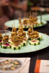 Finger food Chicken Satay with spicy peanut sauce and cucumber salad on a spit on a plate