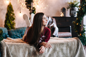 
the girl celebrates the new year and christmas indoors against the background of a Christmas tree of garlands, Christmas decorations and lanterns