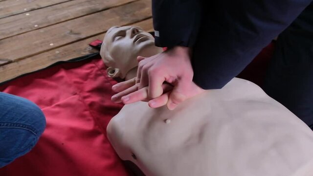 Practicing first aid on mannequin. Practice how to make chest compressions on dummy during the first aid training outdoors.