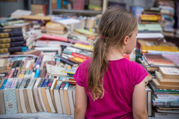 Girl looking at books for sale on a street market in China