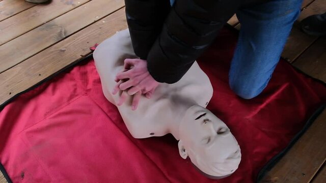 Practicing first aid on mannequin. Practice how to make chest compressions on dummy during the first aid training outdoors.