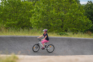 Young girl riding on her bicycle on a dirt race track