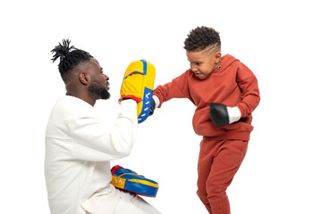 Dark skinned African male teaches his little son to box, isolated