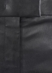 Part of black leather trousers close up
