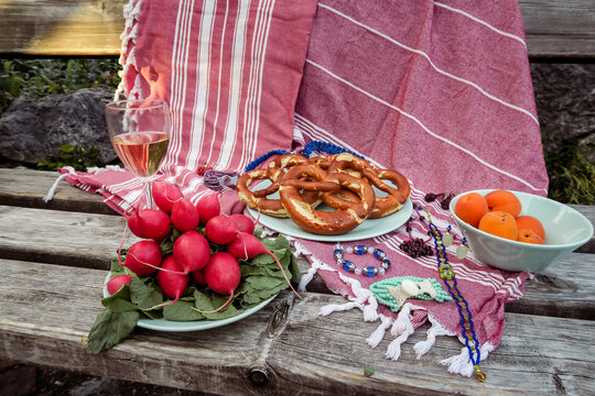 Still life Typical german bavarian picnic on a red blanket on a bench with pretzels, radish, cherries and apricots detail