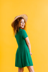 cheerful young woman in straw hat and green dress isolated on yellow