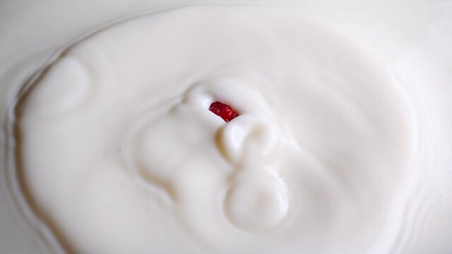 Raspberry falls into milk in slow motion