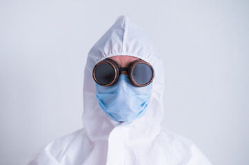 Portrait of a woman in a protective suit wearing a mask with glasses on a white background. A female doctor in uniform during a pandemic.