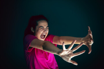 Extreme. Portrait of young crazy scared and shocked caucasian woman isolated on dark background. Copyspace for ad. Bright facial expression, human emotions concept. Looking horror on TV, cinema.