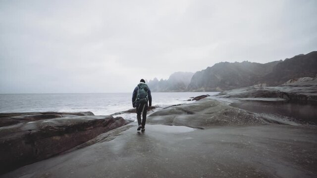 Hiker Walking Over Rocks Near Fjord