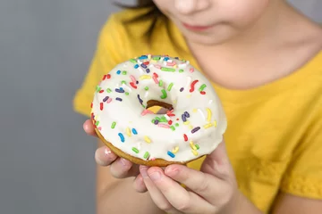 Deurstickers close-up van handen met een geglazuurde witte donut © Albert Ziganshin
