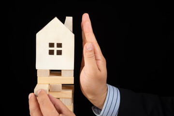 man in suit trying to stop the house falling down from an unstable base concept of policy...