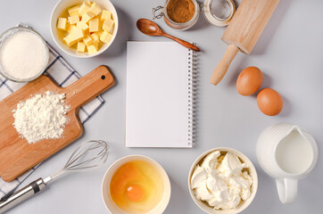 Top view of an empty notepad for writing down a recipe and various ingredients for baking pastry and kitchen tools