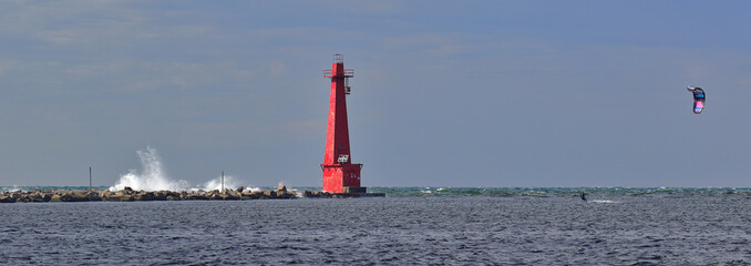 Red lighthouse and breakwater and kite-boarder