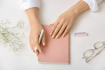 Woman with notebook and pen on light background