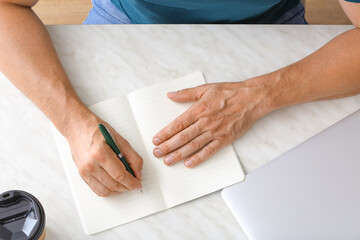 Man writing in notebook with pen