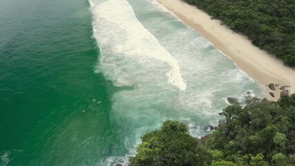 Aerial drone tilt track tropical beach break surfers in Brazil BR UBA 0809 D GR