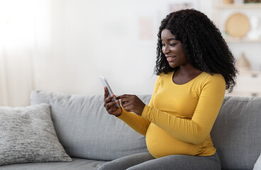 Smiling african american pregnant woman using mobile phone