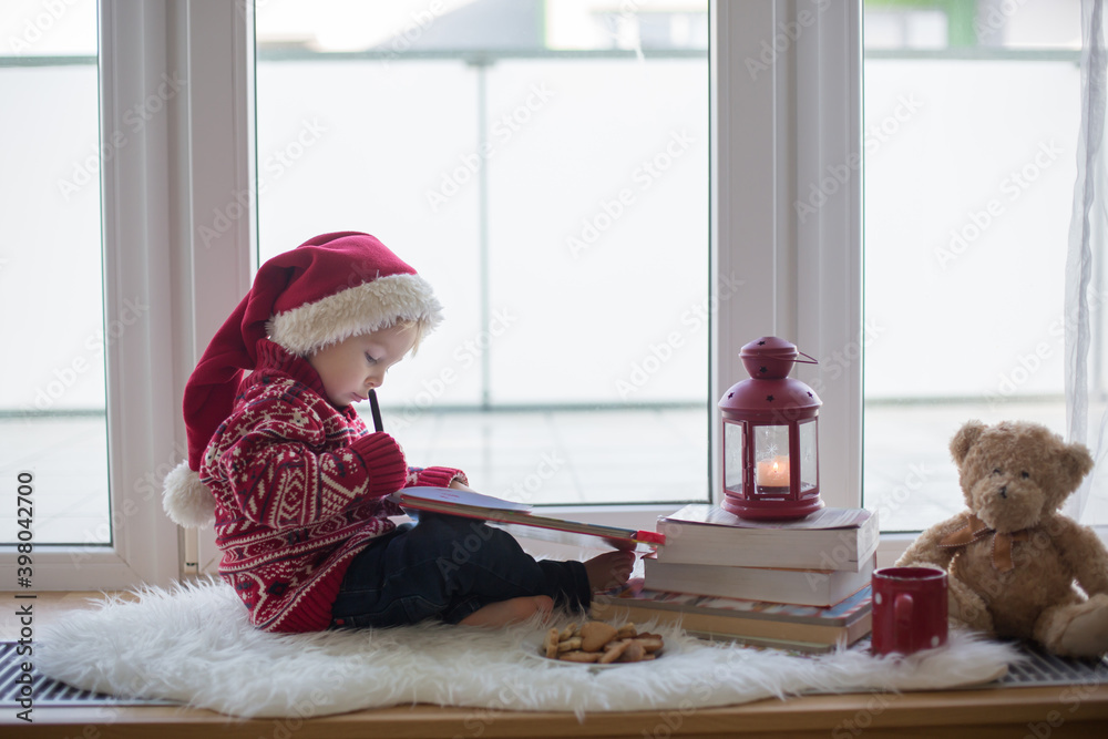 Canvas Prints Sweet blonde child, boy, sitting on window shield with teddy bear friend toy, writing letter to Santa Claus and reading book