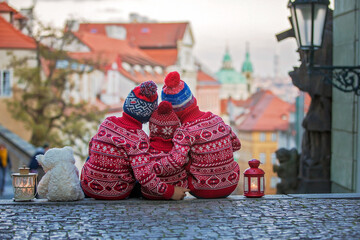 Beautiful children, three boy brothers, casually dressed, looking at night view of Prague city