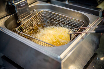 The cook fries food in a deep fryer