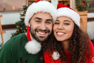 Happy young couple in Santa hats outdoors