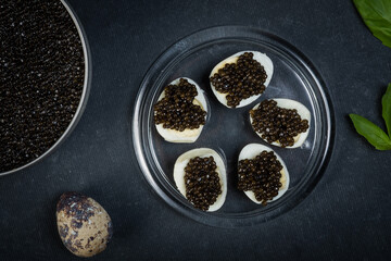 Festive New Year's treat. Sandwiches with black caviar sturgeon on a blue round plate on a dark background.