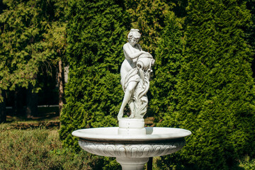 White statue of a girl with a jug in the park