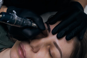 Permanent eyebrow makeup procedure. Eyebrow tattooing, process. The use of tools by a master for permanent eyebrow makeup.