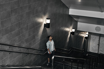 A young guy comes down the stairs, an underground passage. Subway, stairs down.
